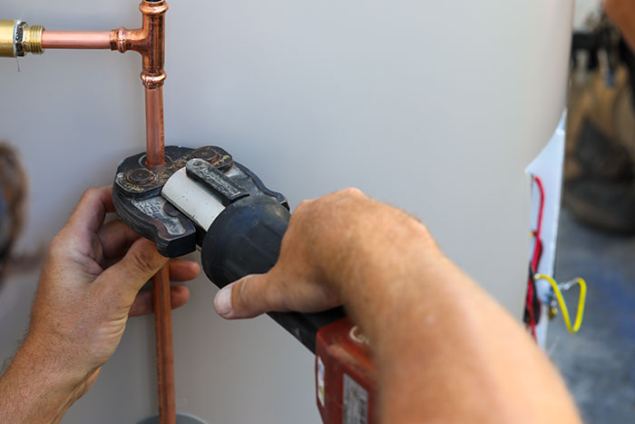 Plumber crimping copper pipes on a hot water system in Brisbane